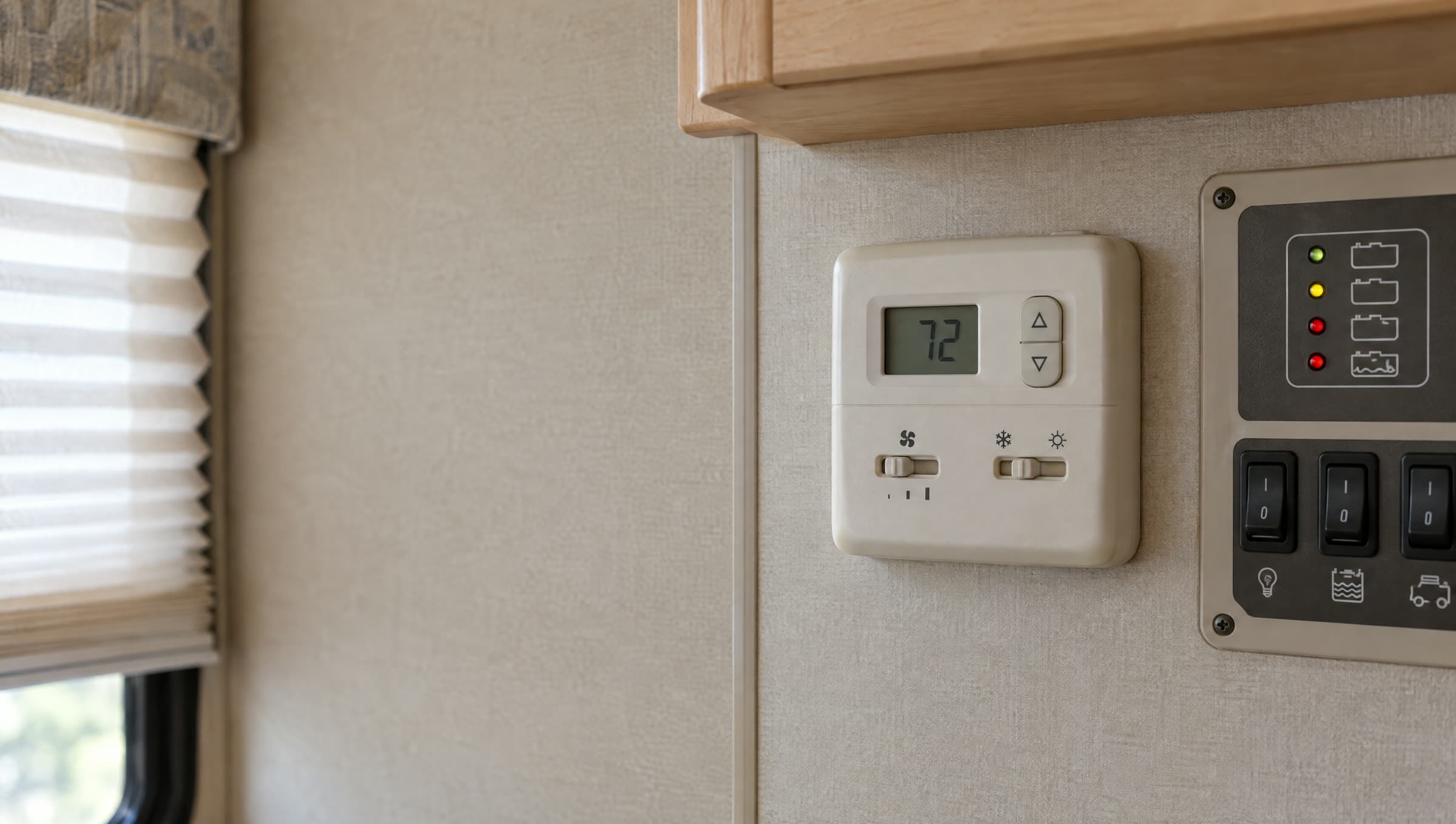 An old beige RV thermostat on dated wood paneling